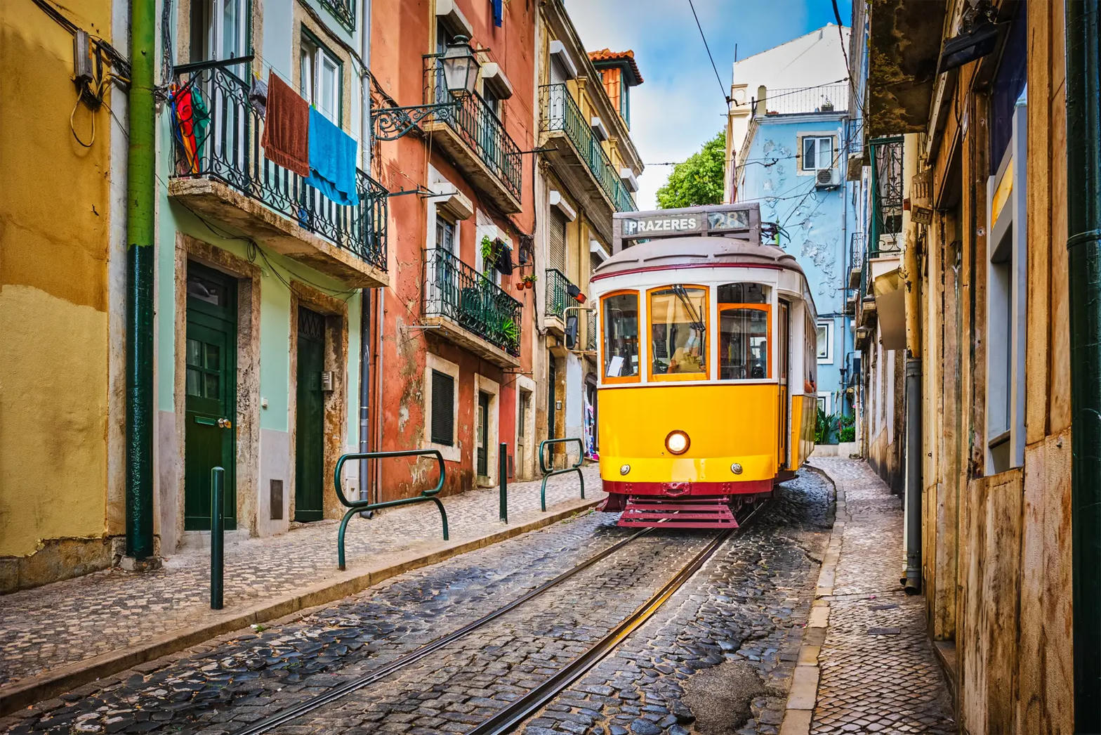 Yellow tram on a narrow cobblestone street in Lisbon